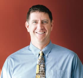 Dr. Tyler Karlin, smiling, in a blue shirt and tie